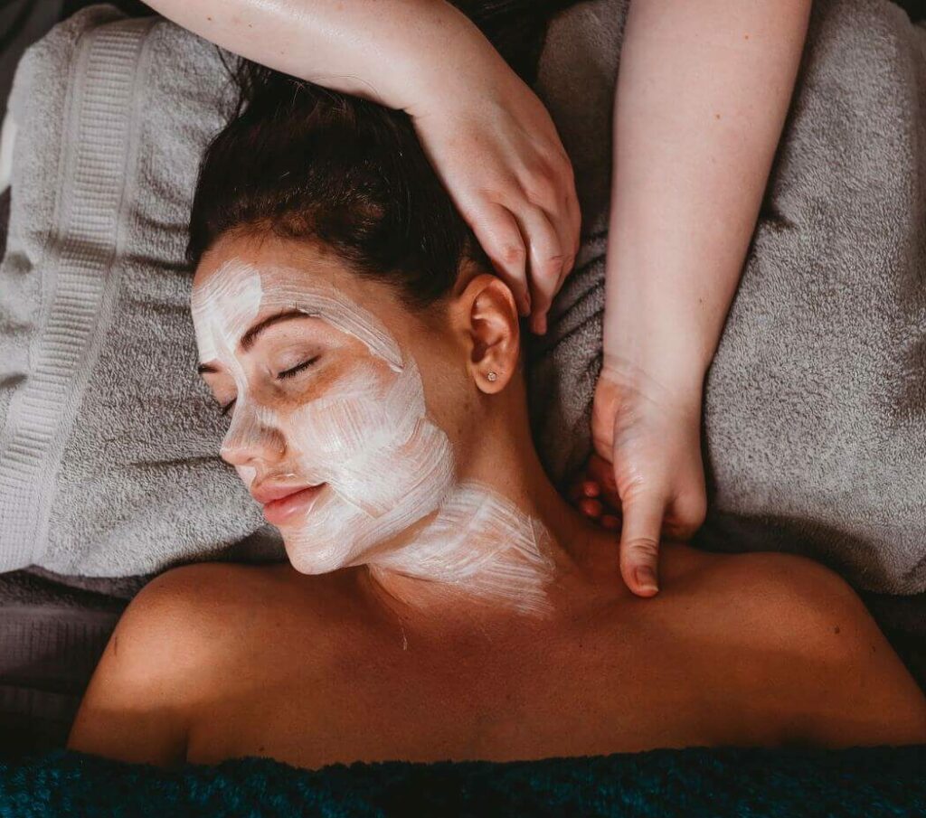 A woman getting a facial mask and massage at a spa